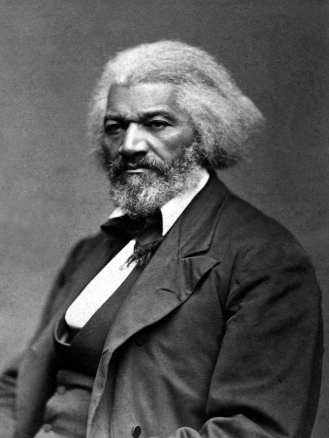 A portrait photograph of Frederick Douglass, seated, with white hair and a dark suit